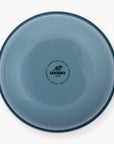The bottom of a smoky blue rolled enamel bowl on a white background