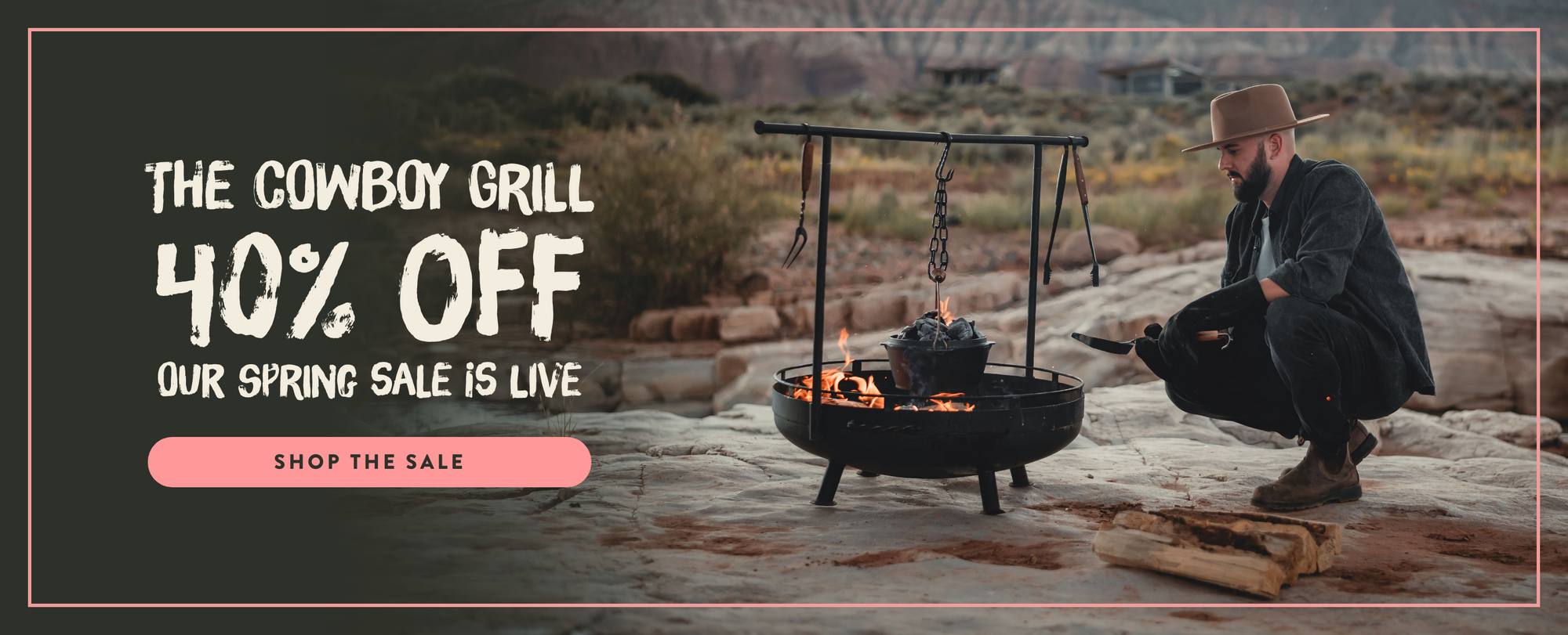 Man by a cowboy grill with promotional banner for a grill sale with a discount offer.