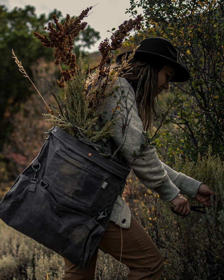 Woman foraging with Pruners and a Gathering Bag in the mountains.