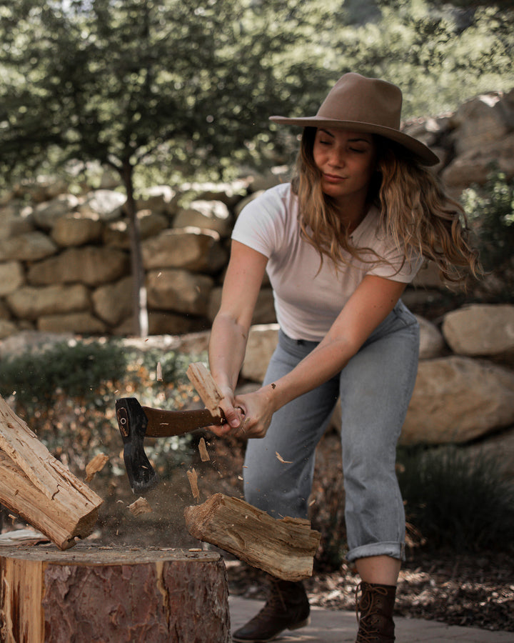 Woman striking a log with a Felling Axe in a backyard.